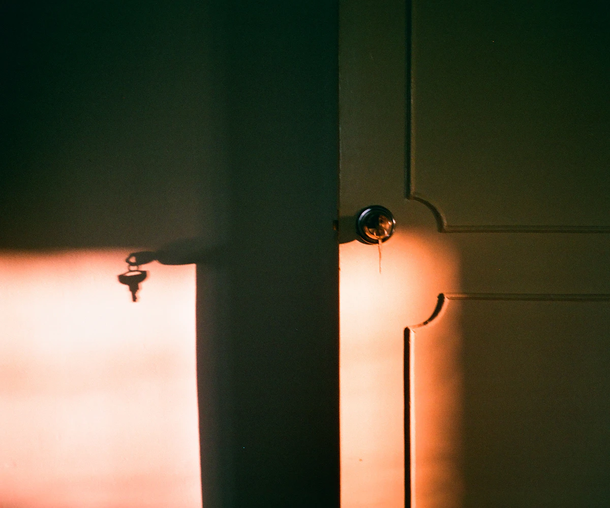 Keys hanging by a door left slightly open, light coming through